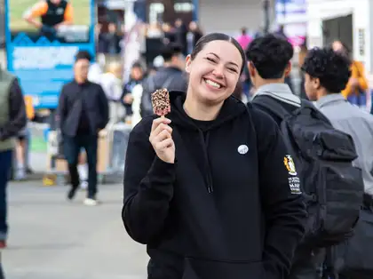 A smiling wahine holding an ice cream at Massey University Open Days.